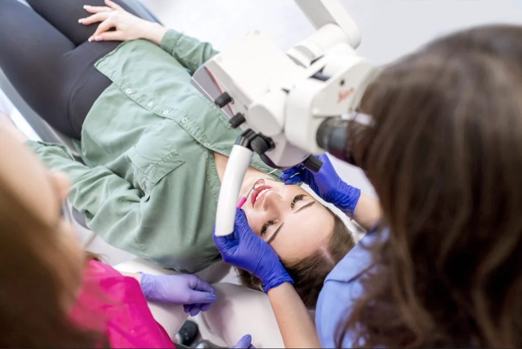 Leczenie kanałowe zęba Kraków, doktor Kopycińska używa mikroskopu przy zabiegu stomatologicznym.