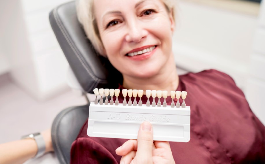 Uśmiechnięta kobieta z próbnikiem kolorów zębów, etap protetyczny