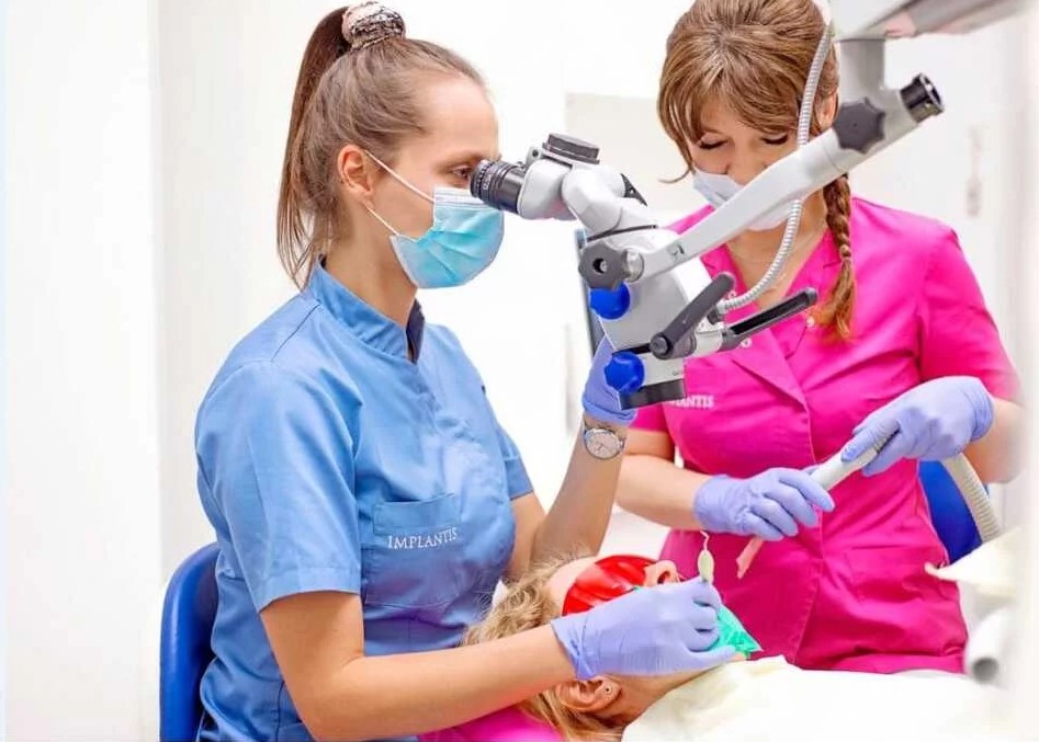 Leczenie endodontyczne Kraków, doktor Magdalena Koralewicz używa mikroskopu przy zabiegu stomatologicznym.