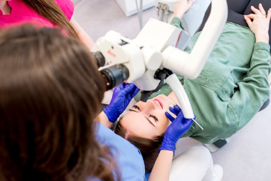 Dentystka Natalia Kopycińska przeprowadza badanie pod mikroskopem stomatologicznym pacjentki.