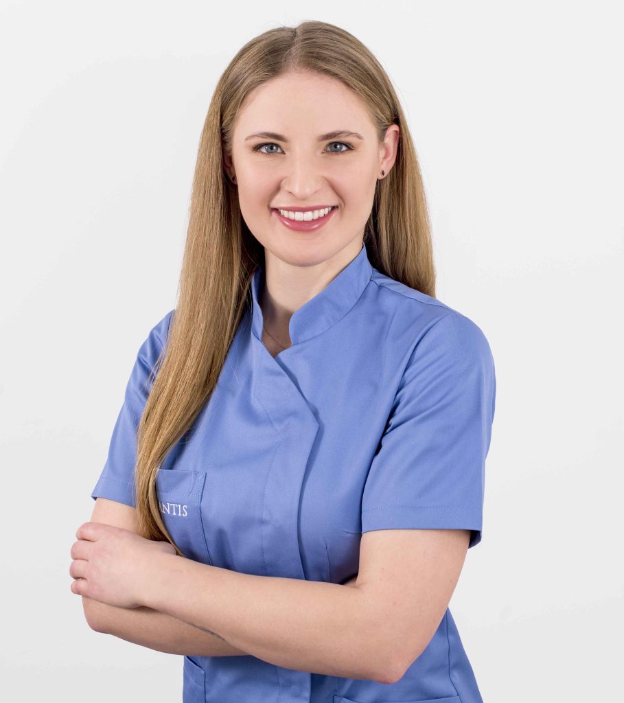 Stomatolog Paulina Atalska z gabinetu Implantis, portret w niebieskim uniformie medycznym, 
